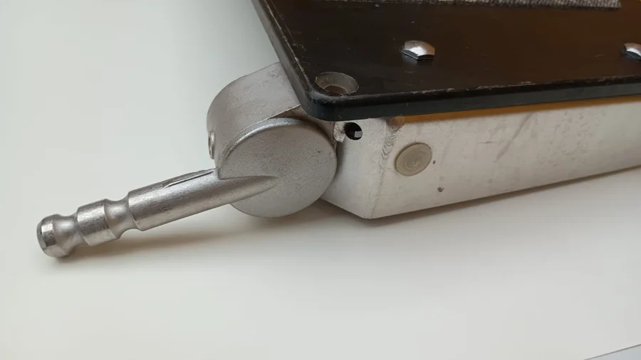 Eje y pivote metálico de un accesorio clínico desmontado para revisión